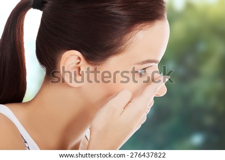 Woman applying contact lens in her eye.
