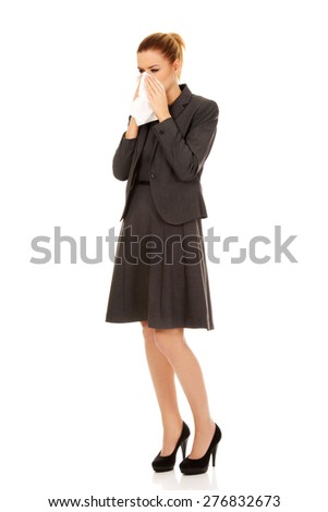 Businesswoman with an allergy sneezing into tissue.