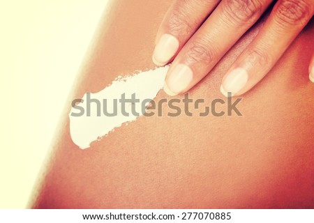 Close up slim woman applying cream on thigh.