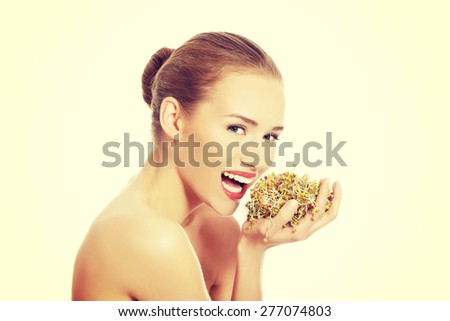 Nude woman eating sunflower sprouts.