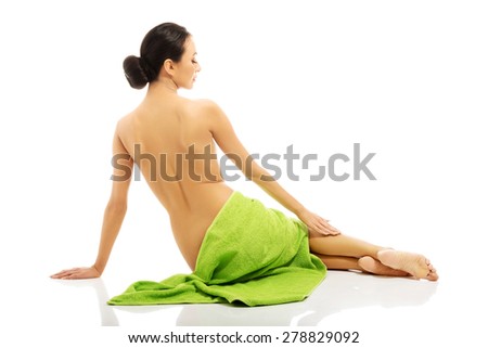 Back view of woman lying wrapped in green towel