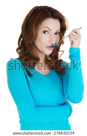 Portrait of young smiling woman with spoon in her mouth