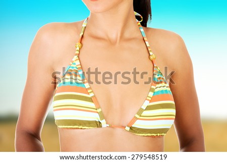 Beautiful tanned woman\'s breast in bikini.