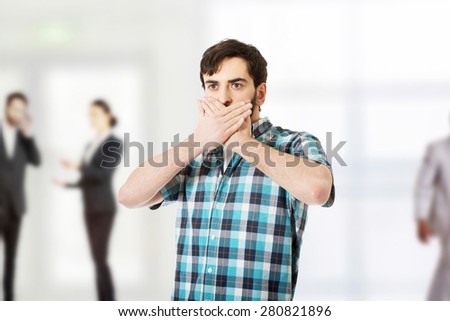 Young handsome shocked man covering his mouth.