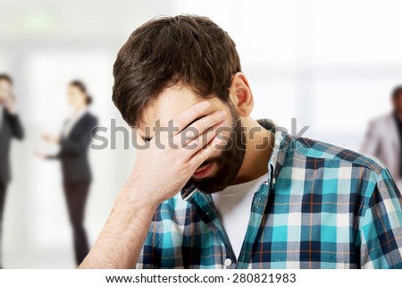 Young upset man covering his face.