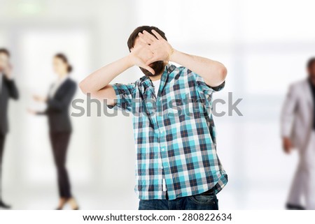 Young handsome afraid man covering his face.