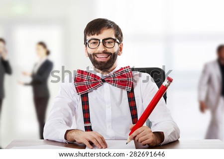 Funny old fashioned man sitting by a desk with big pencil.