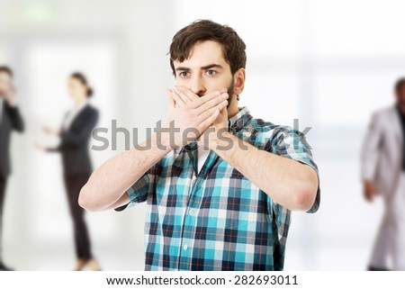 Young handsome shocked man covering his mouth.
