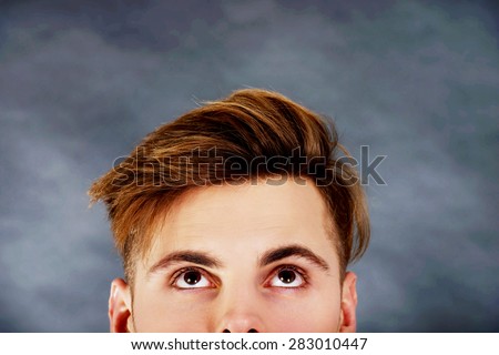 Handsome young man with brown eyes looking up.