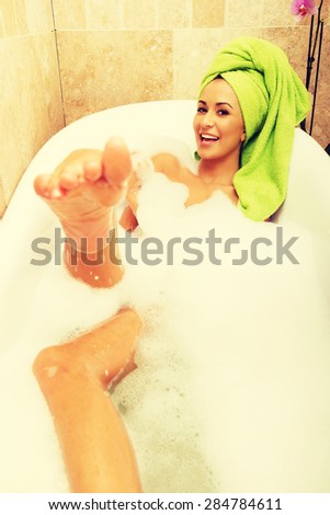 Funny woman relaxing in bath looking at the camera.