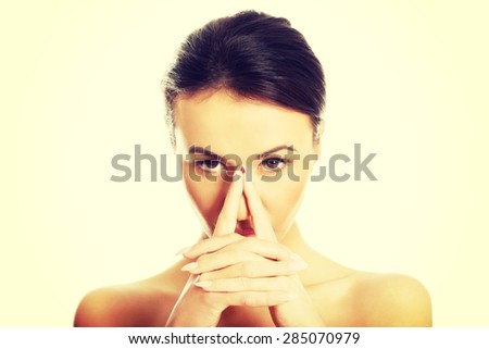 Portrait of serious nude woman holding nose and looking at the camera.