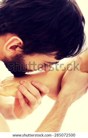 Handsome young man kissing woman\'s bare feet.