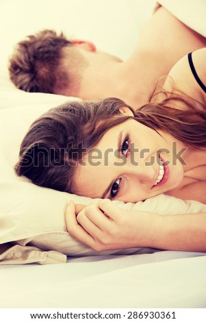 Young happy smiling woman and sleeping man in bed.