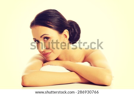 Serene woman lying on a rolled towel with folded arms.