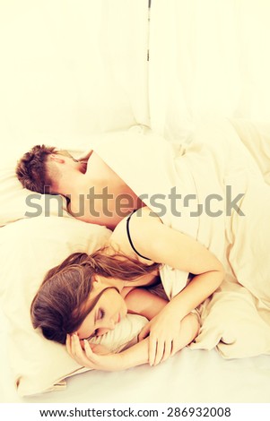 Young thoughtful woman and sleeping man in bed.