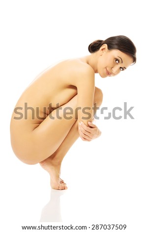 Beautiful nude woman curled up on the floor, standing on fingers