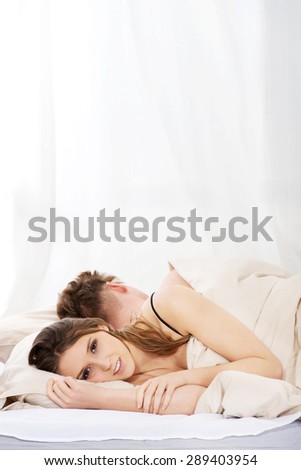 Young woman and sleeping man in bed.