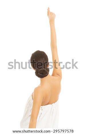 Back view woman wrapped in towel pointing up.