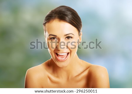 Portrait of nude woman laughing loud, looking at the camera.