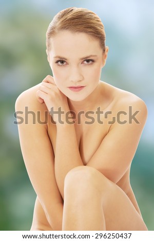 Young spa woman sitting on the floor with her knees close to chest.