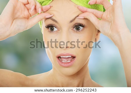 Beauty woman checking wrinkles on her forehead, closeup