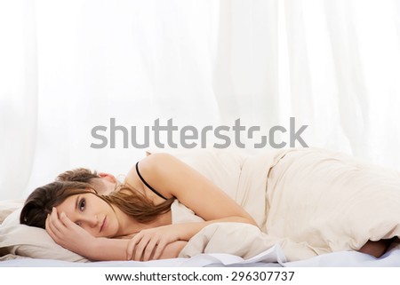Young thoughtful woman and sleeping man in bed.