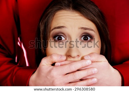 Scared woman has mouth covered by a man.