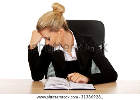 Tired businesswoman writing note by a desk.