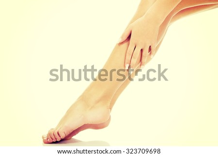 Slim woman touching her slim legs.