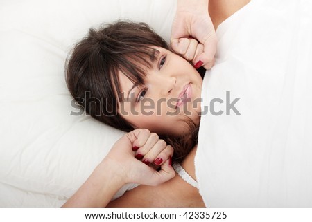 Lazy beautiful woman in bed stretching and yawns