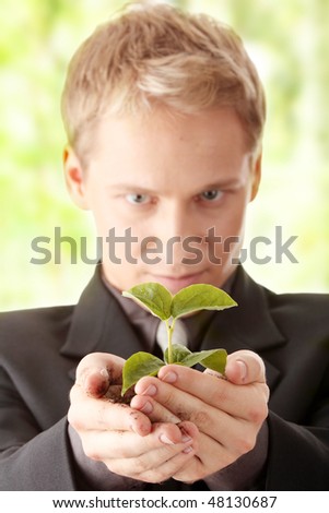 Businessman in dark suit holding small plant in his hands - growth concept