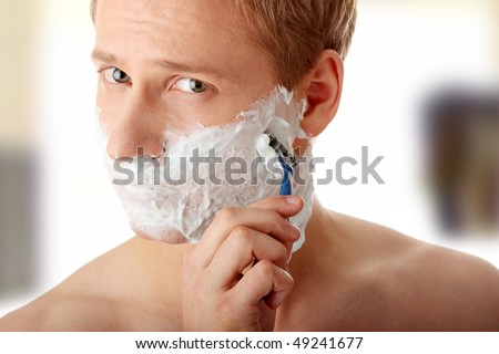 Young caucasian man is shaving his self