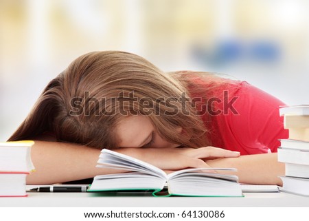 Teenage girl studying at the desk being tired