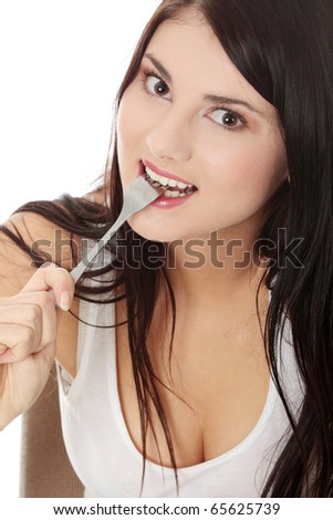 Portrait of young smiling woman with fork in her mouth and (pleasure from eating), isolated on white