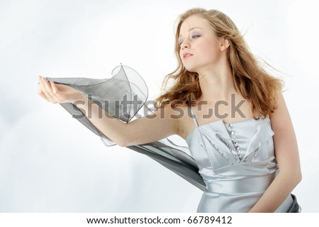 Young beautiful blond woman in elegant, evening, silver dress dancing with wind (hair blowing)