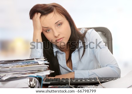 Exhausted female filling out tax forms while sitting at her desk.