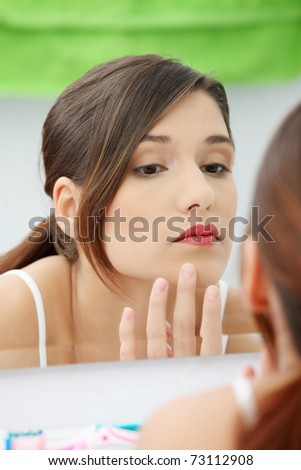 Young beautiful caucasian woman stands about a mirror in a bathroom