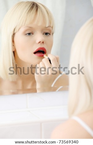 Woman making up her lips at bathroom