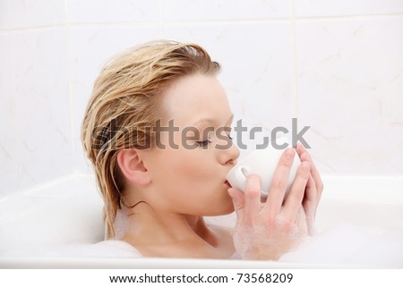 Young beauty woman in the bath drinking herbal tea or coffee