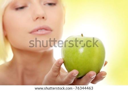 Beautiful blond woman with green apple. Over abstract green background