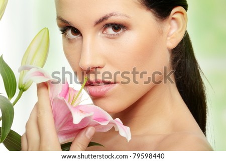 Beautiful young woman face with perfect skin with lily flower.