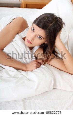 Young pretty girl lying in bed. Sad thinking