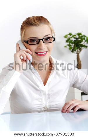 Young beautiful woman answering the phone in the office.