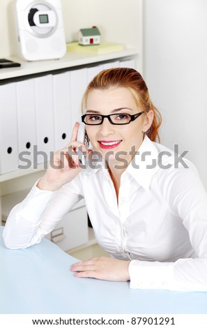 Young beautiful woman answering the phone in the office.
