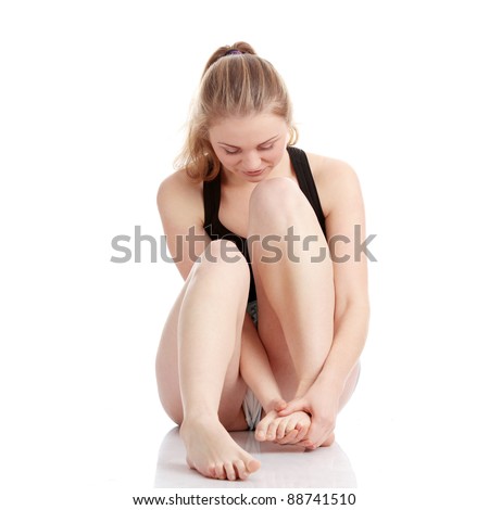Beautiful young blond woman experiencing leg cramp after a physical activity, isolated on white background