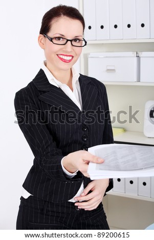 Pretty caucasian standing businesswoman giving files.