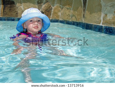 Young girl in a floppy hat in a suburban pool