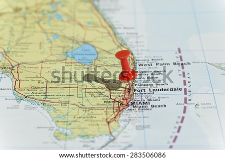 Fort Lauderdale marked on map with red pushpin. Selective focus on the word Fort Lauderdale and the bottom of pushpin. Pin is in an angle and casts shadow to the left.