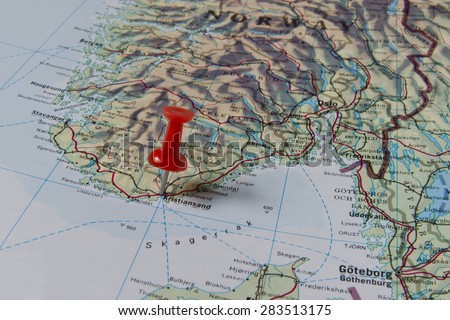 Kristiansand marked with red pushpin on map. Selected focus on Kristiansand and bright red puspin. Pushpin is in an angle. Southern parts of Norway can be seen on map.