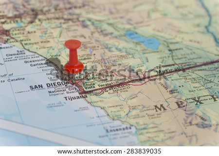 San Diego marked on map with red pushpin. Selective focus on the word San Diego and the bottom of pushpin. Pin is in an angle and casts shadow to the left.